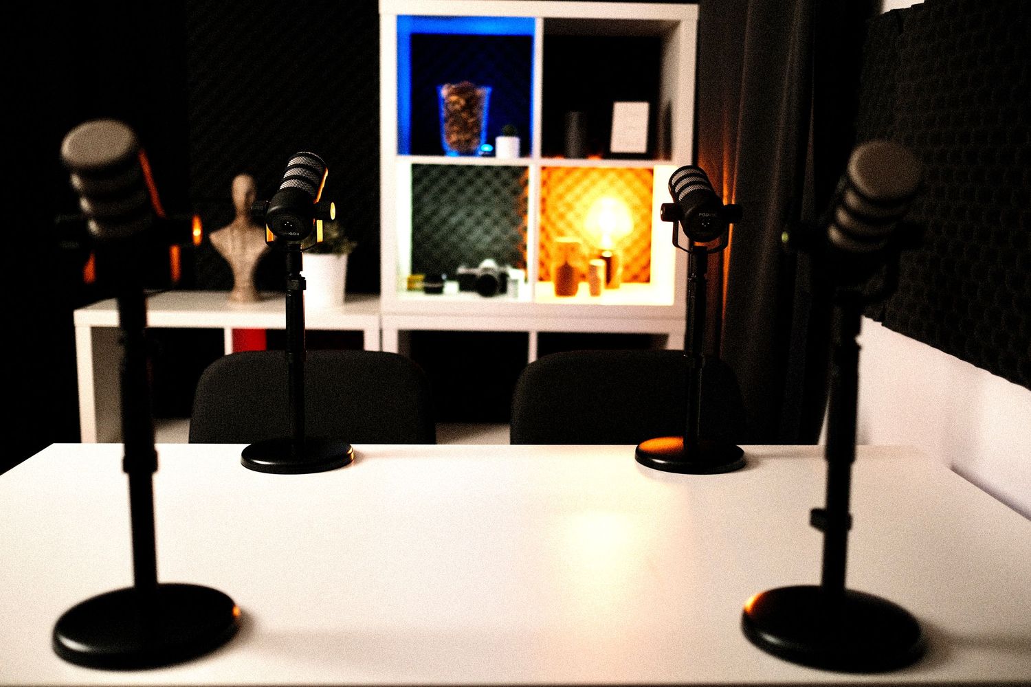 Recording studio space with white furniture and blue accent lighting.