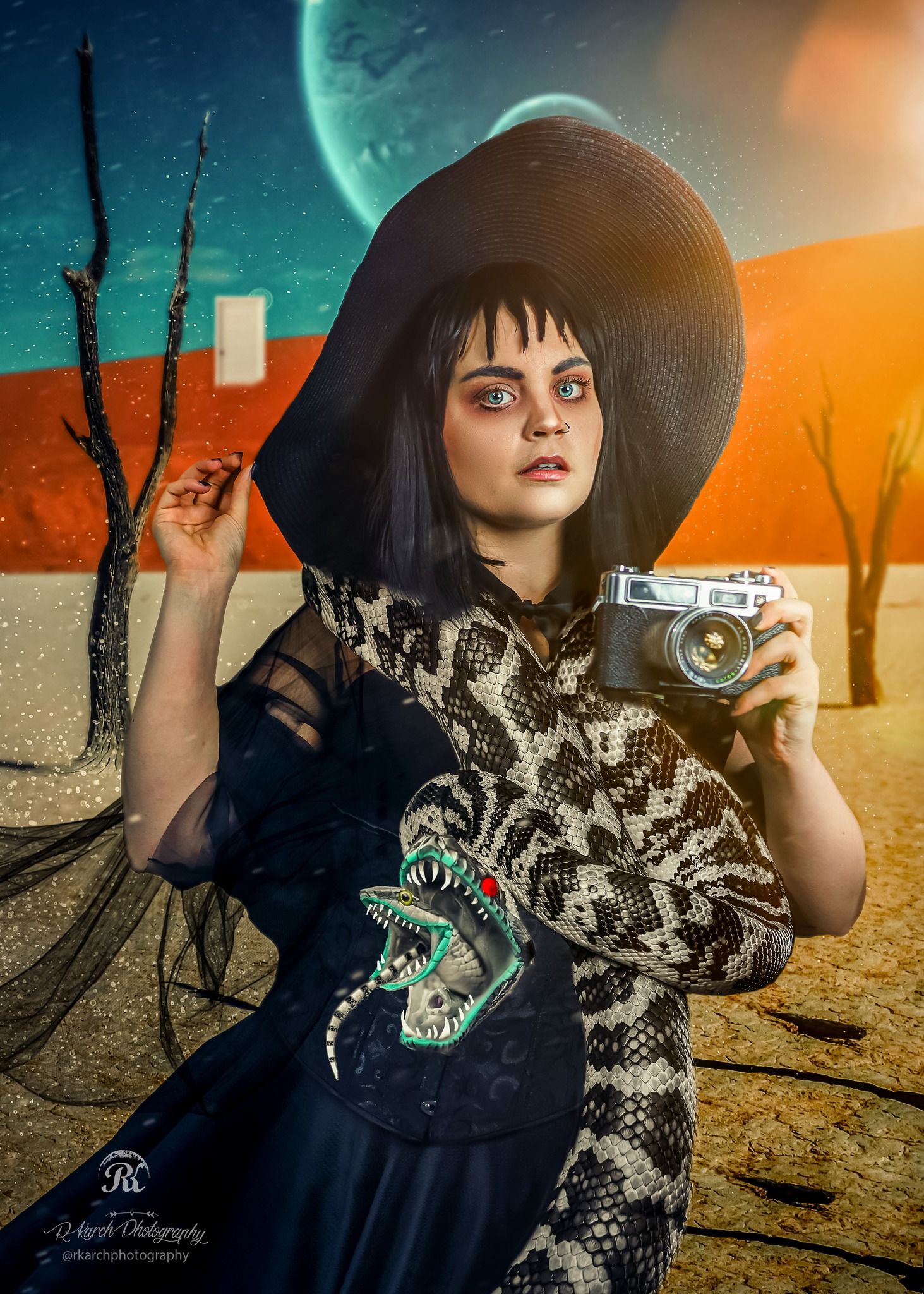 Artistic portrait of a girl in a wide-brimmed hat holding a vintage camera against a surreal desert backdrop.