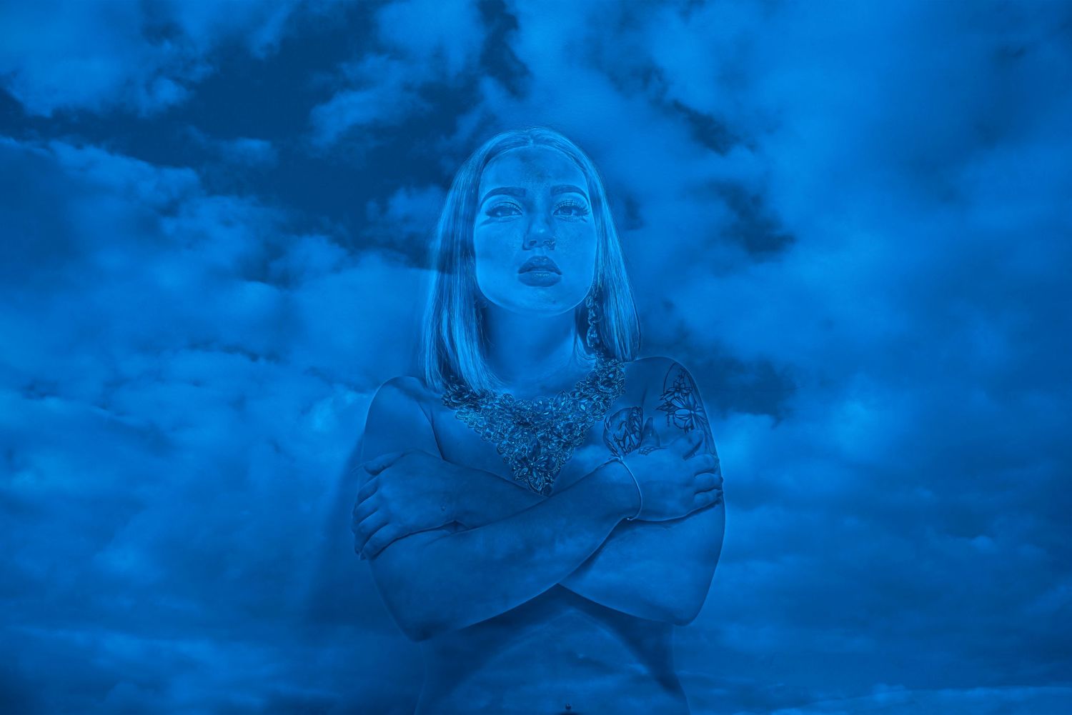 Ethereal blue-tinted portrait silhouetted against cloudy night sky.
