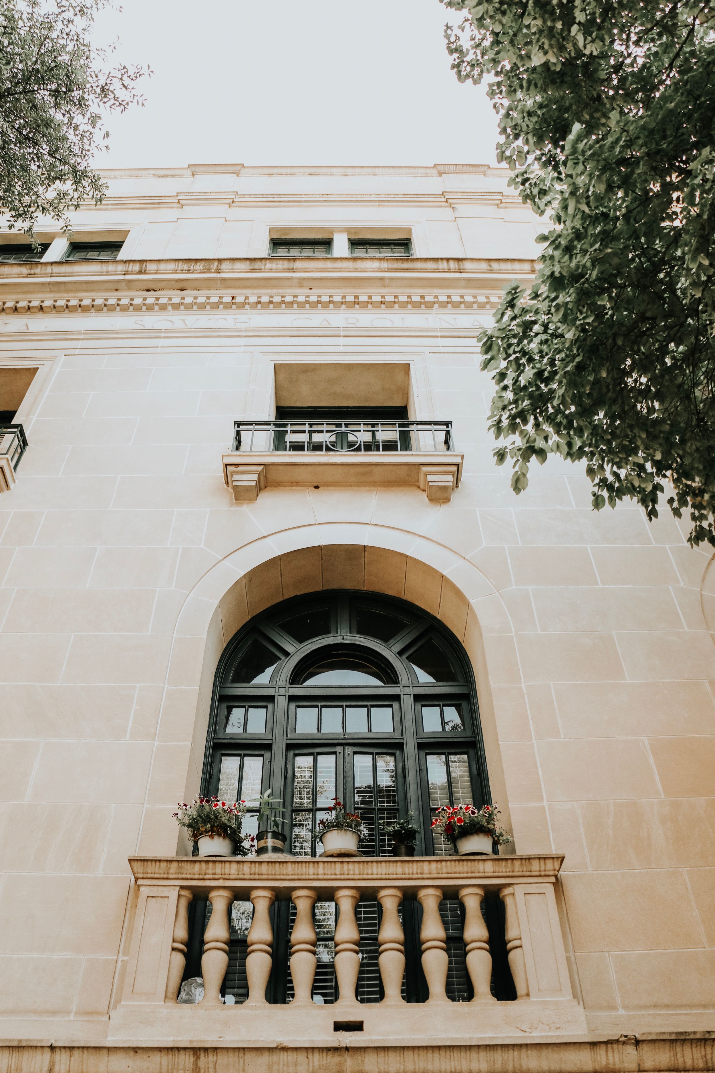 Classical white building facade with arched window, ornate balcony and decorative details.
