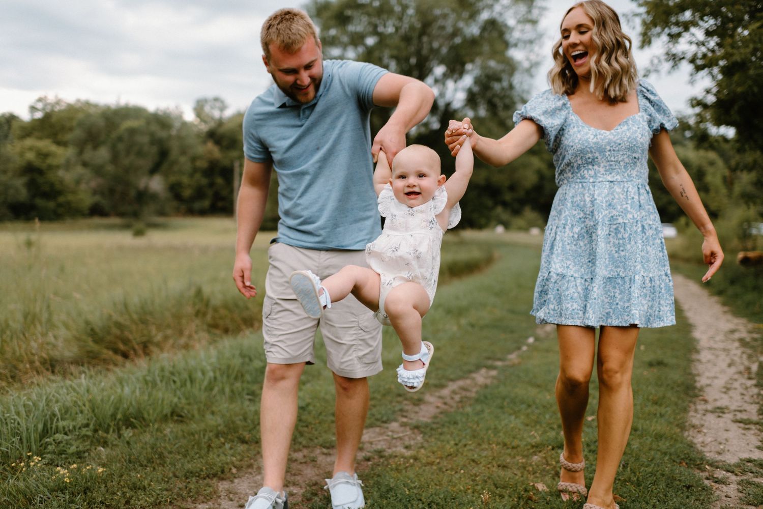 A joyful family moment captured on a dirt path in a sunny meadow.