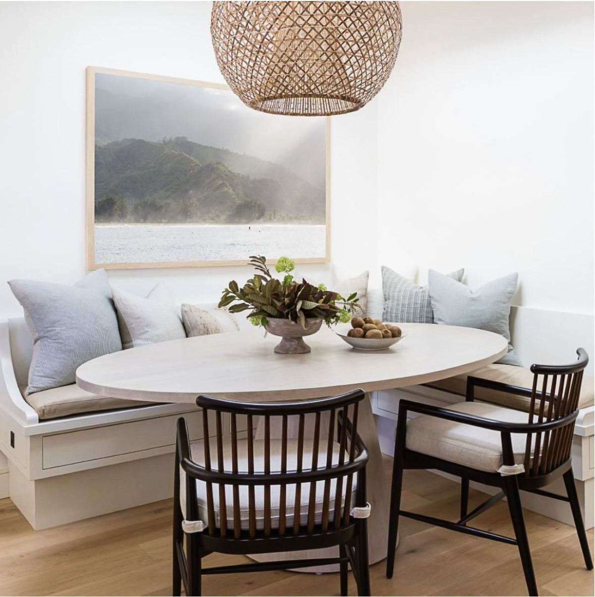 Modern dining nook with built-in bench seating, round table, and woven pendant light.