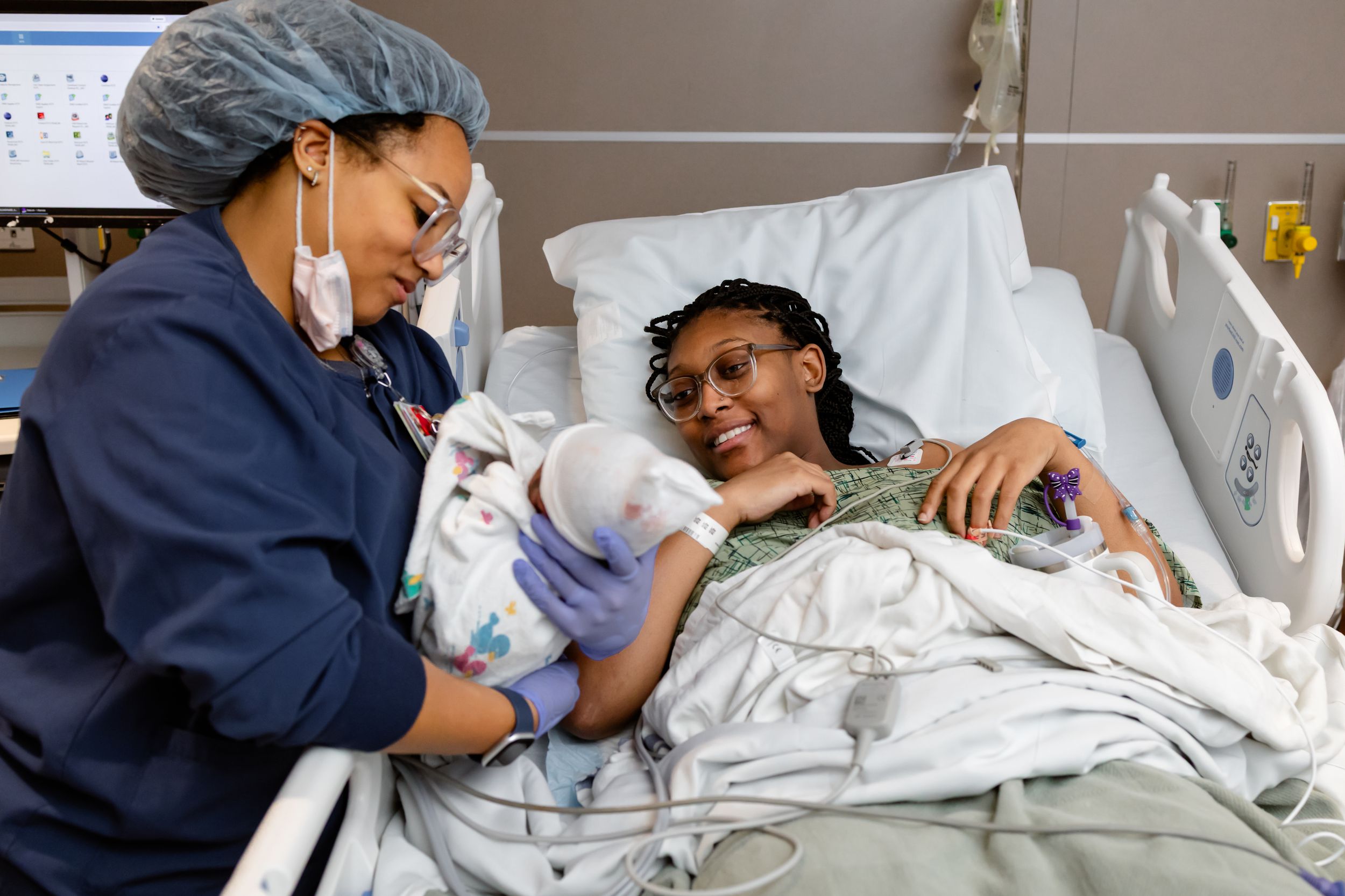 Healthcare worker comforting patient in hospital bed while checking vital signs and providing medical care.