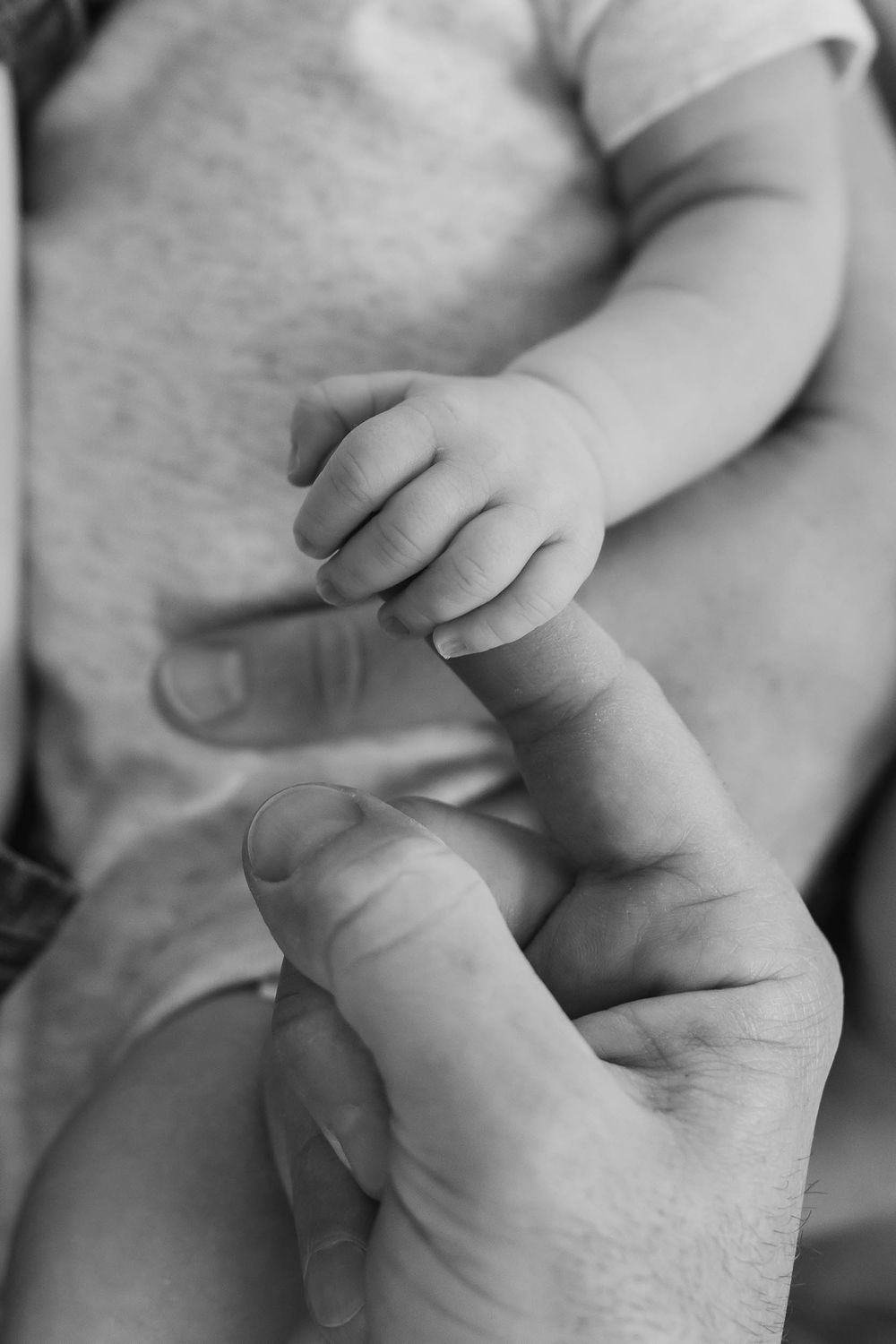 Close-up black and white image sequence of two hands holding and intertwining fingers in tender moments.