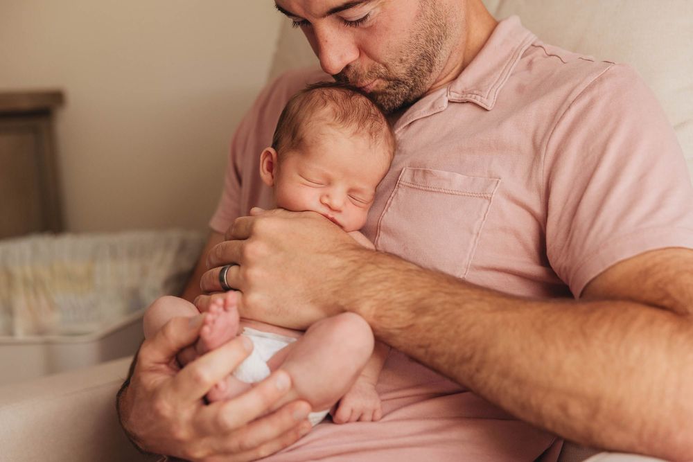 A person holds a sleeping baby swaddled in a white blanket with multiple sequential views of the tender moment.