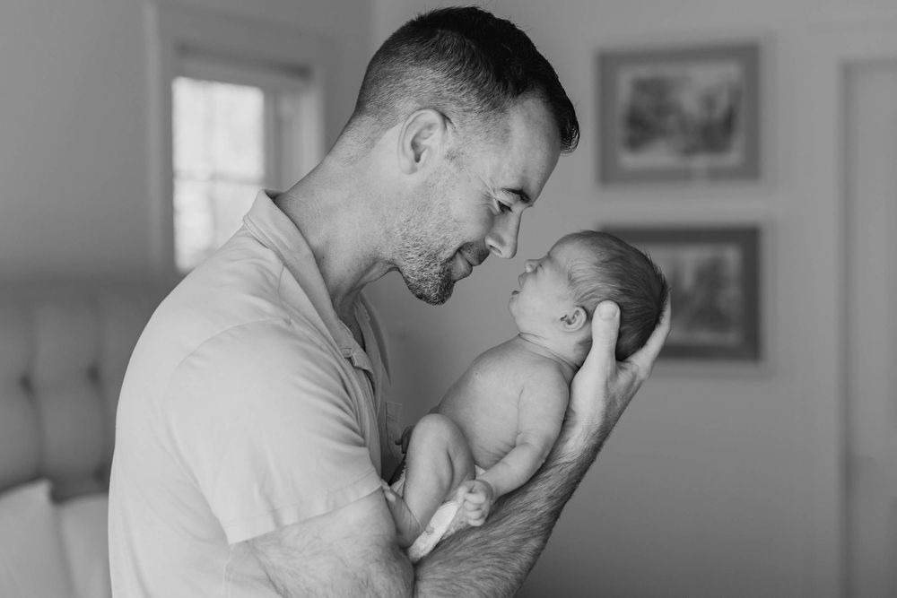 A tender moment between adult and child sharing laughter in a casual home setting.