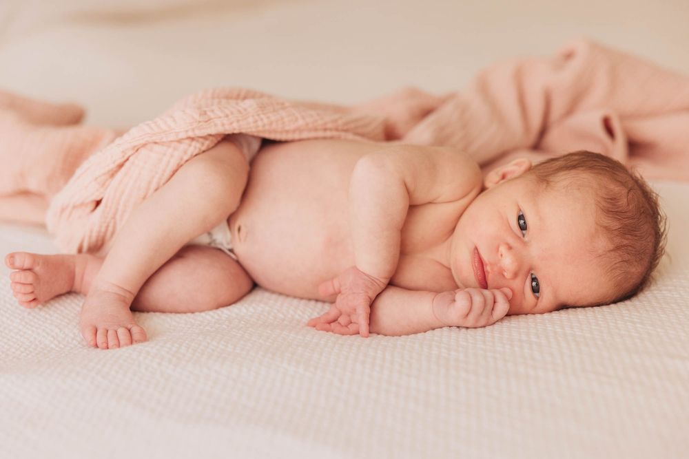 A collage of peaceful infant poses on soft beige fabric in a baby photography session.