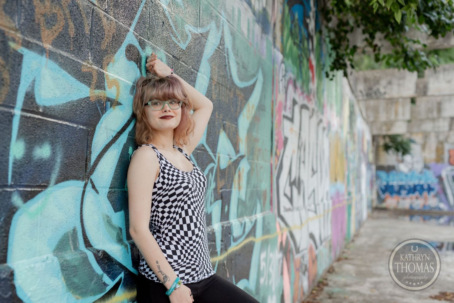 A retro-styled pose against blue graffiti wall wearing geometric print tank top.