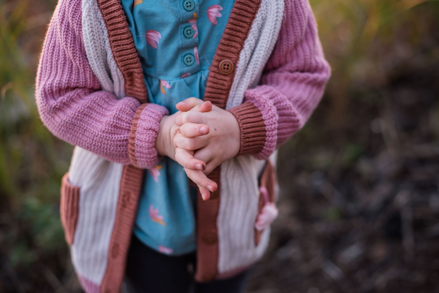 Colour detail image of a Caucasian girl holding her hands together.