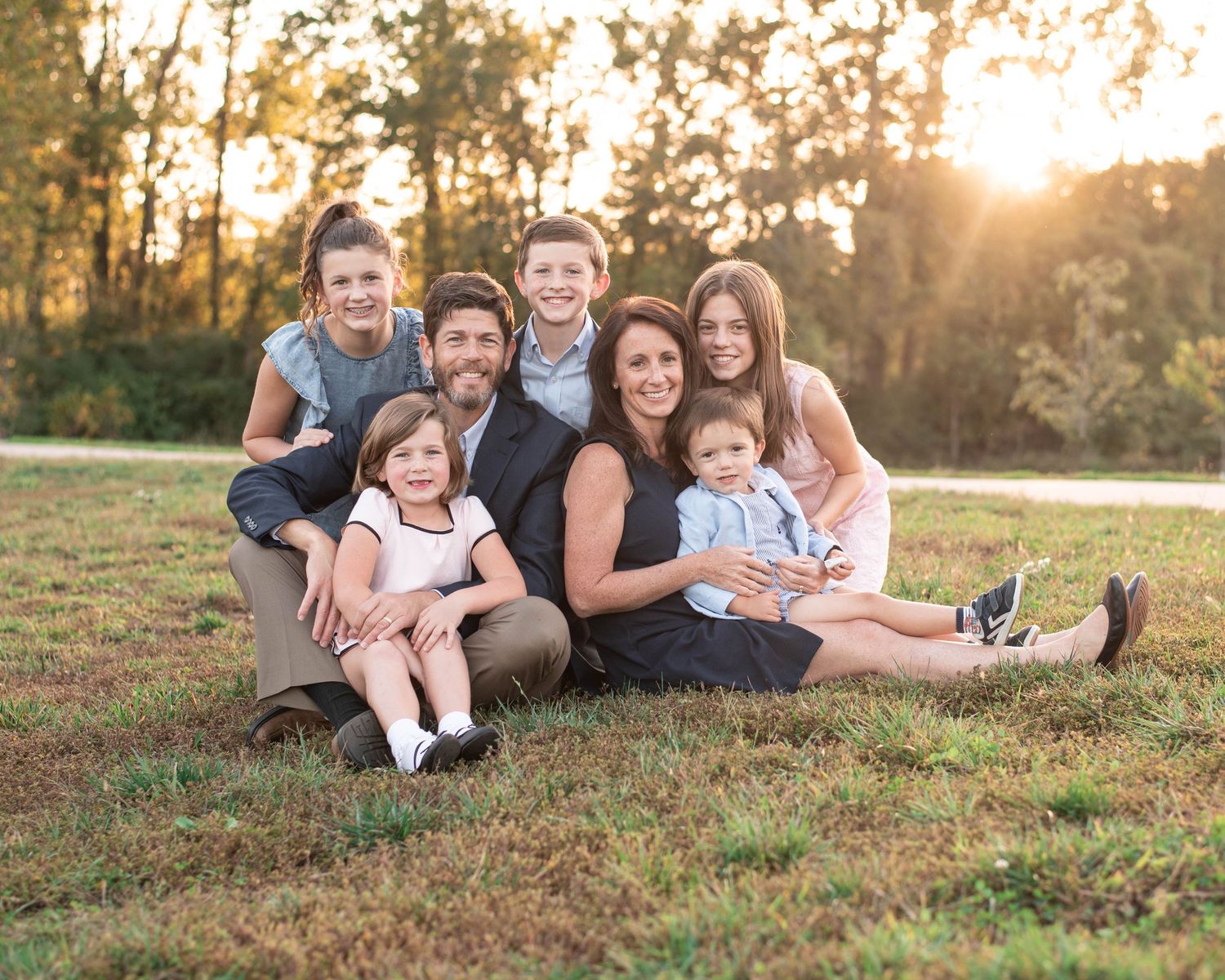 Family of seven dressed in pink and blue, smiling.