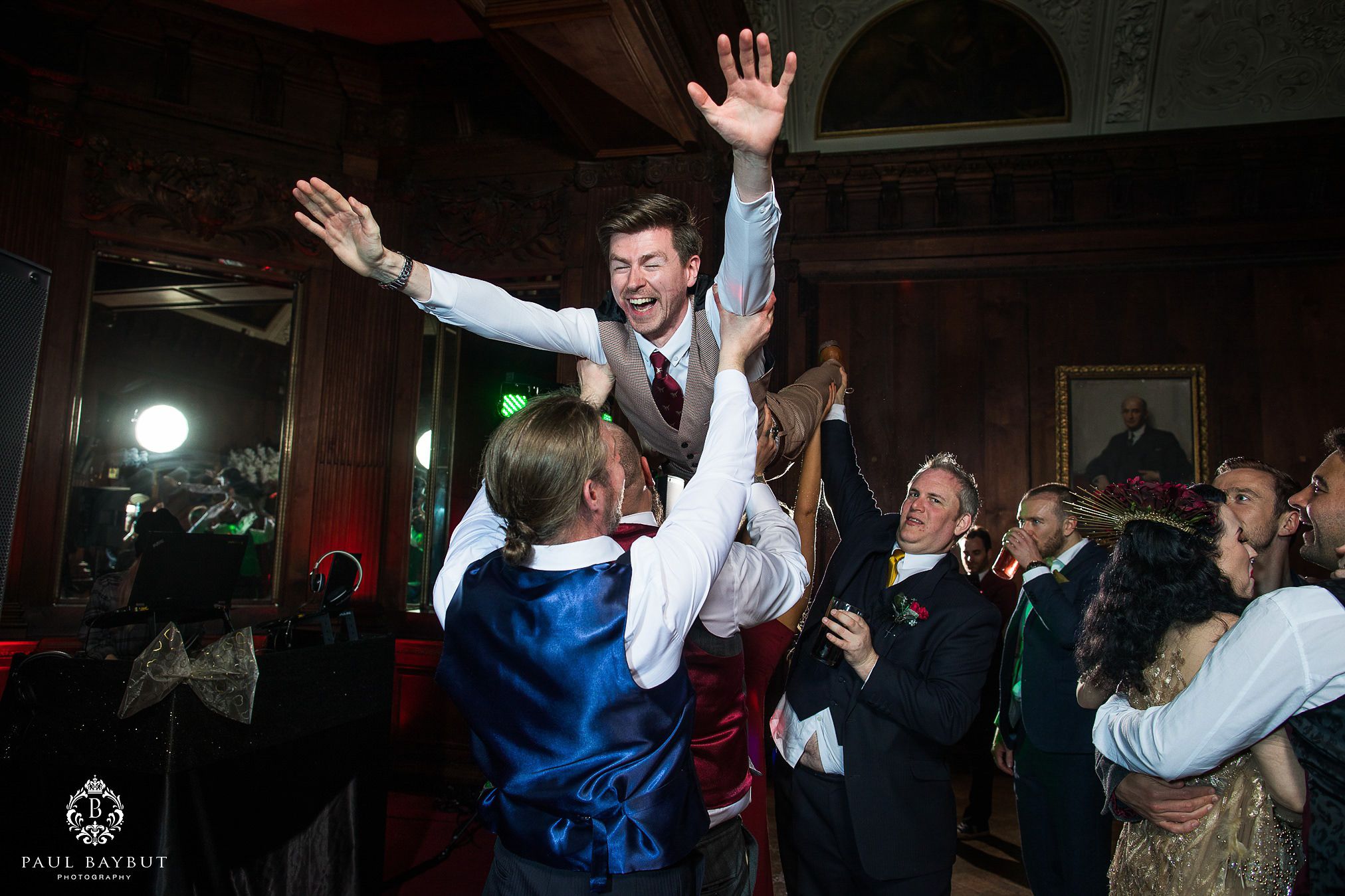Wedding guest gets lifted up by the crowd during an energetic reception celebration.