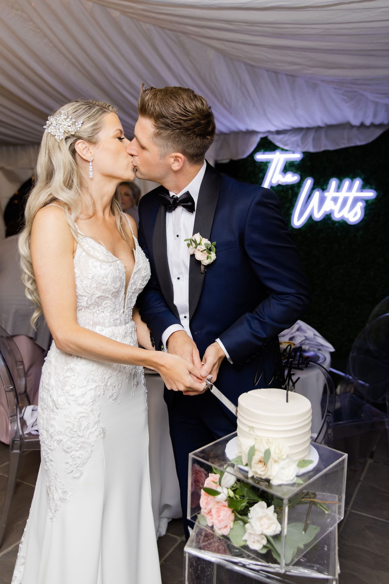 Romantic moment shared by newlyweds while cutting their elegant white wedding cake.