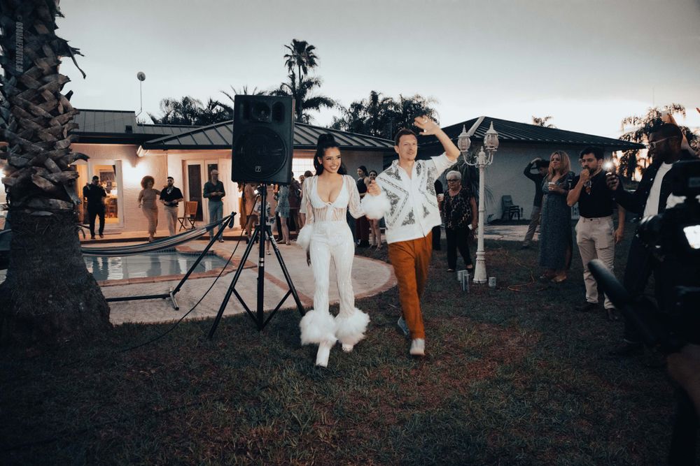 Wedding celebration at dusk with guests mingling around outdoor reception area.