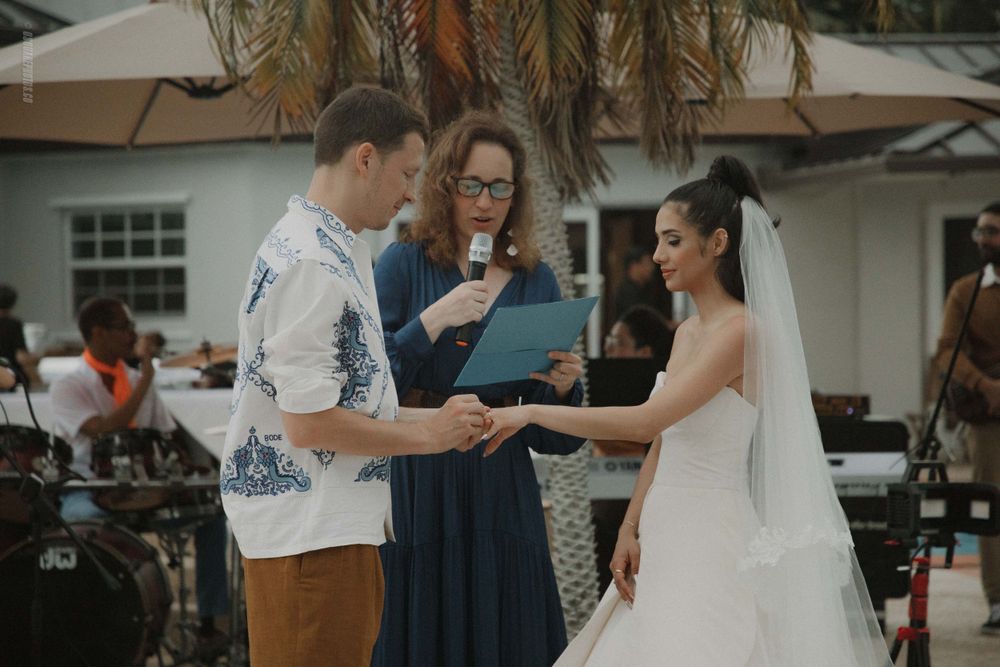Wedding ceremony moment with officiant in blue dress conducting the service outdoors.