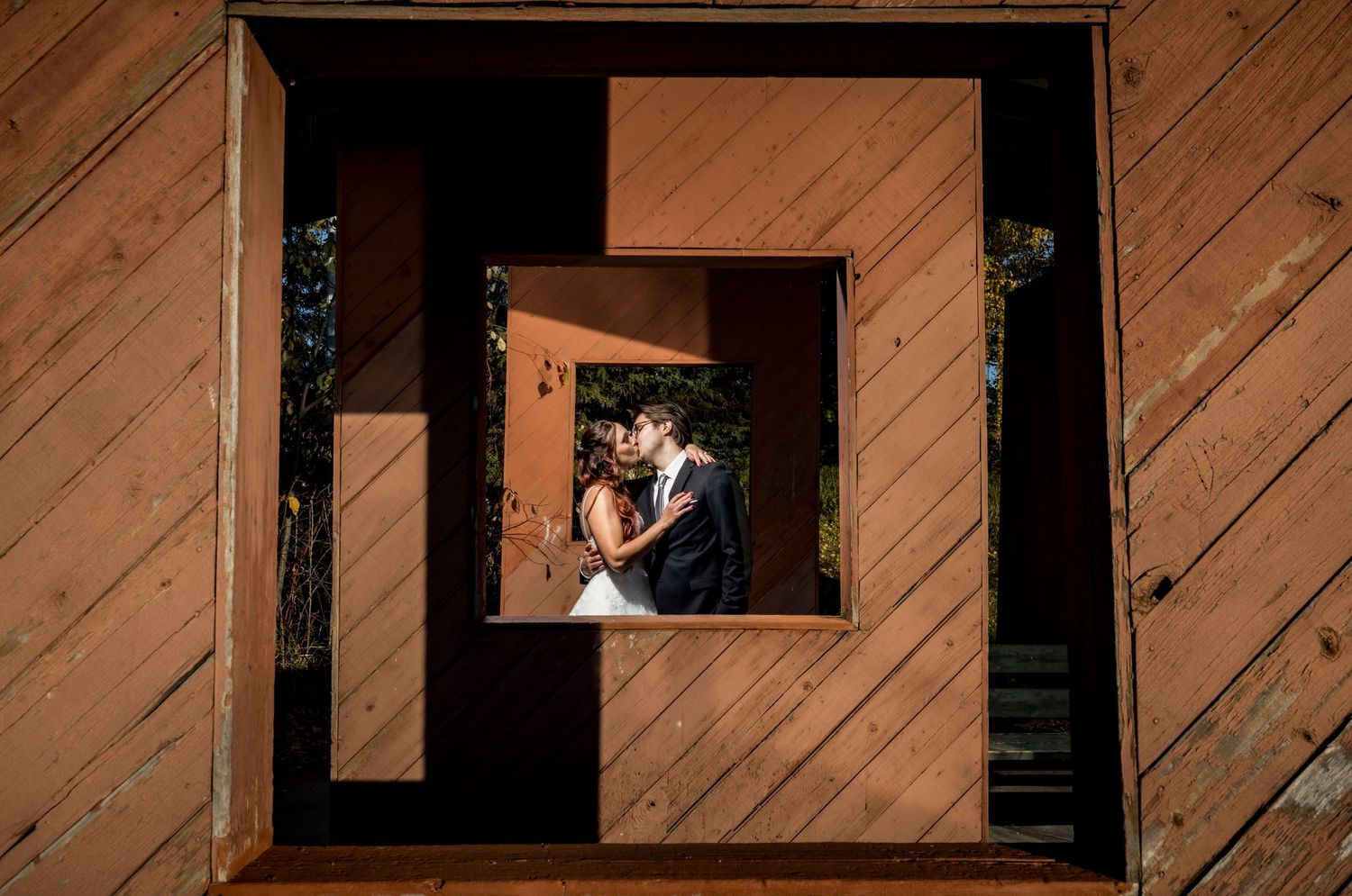 Creative wedding photos taken through wooden window frames of rustic building.