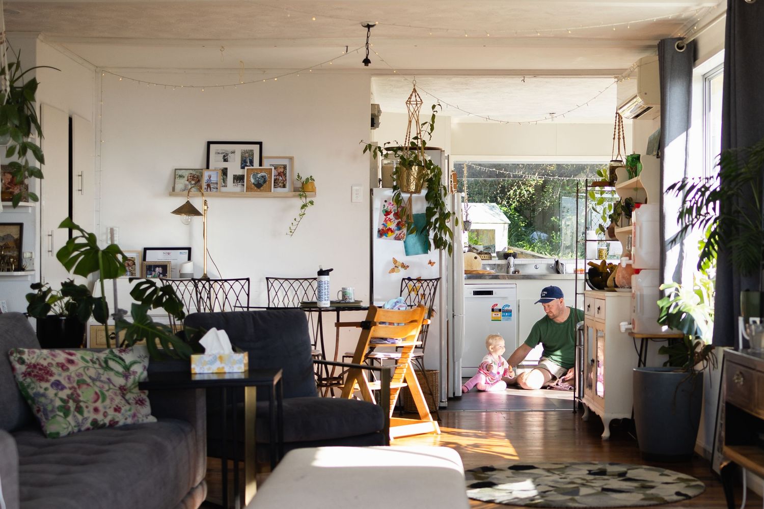 Wide angle shot of a father and daughter as they sit on the kitchen floor with the light pouring in from the window.
