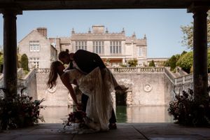 A couple share a dip kiss in the boathouse at Euridge Manor, luxury Cotswolds wedding venue