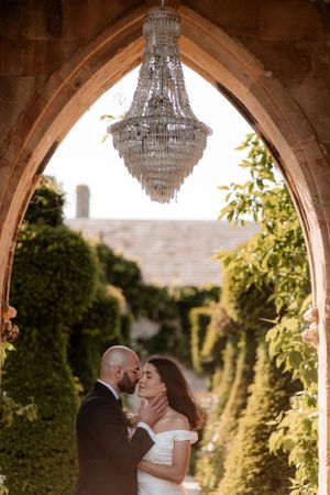A couple share a kiss under the chandelier at Euridge Manor, luxury Cotswolds wedding venue