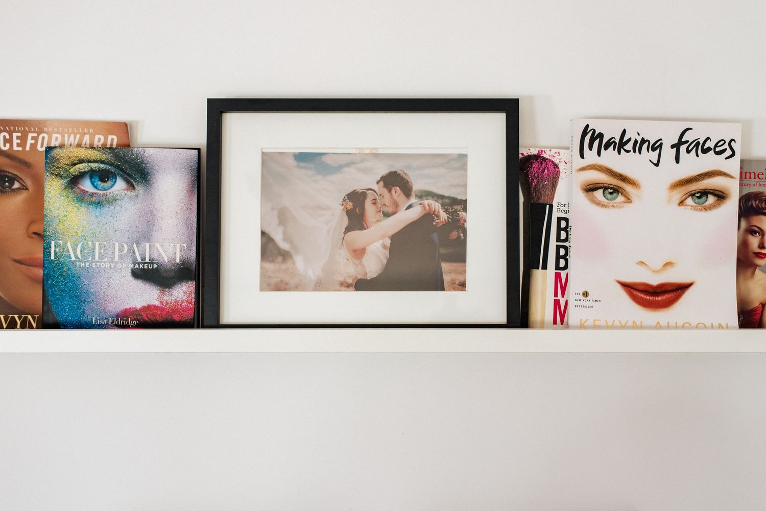 Shelf displaying three album covers including beauty-themed artwork and a framed photograph.