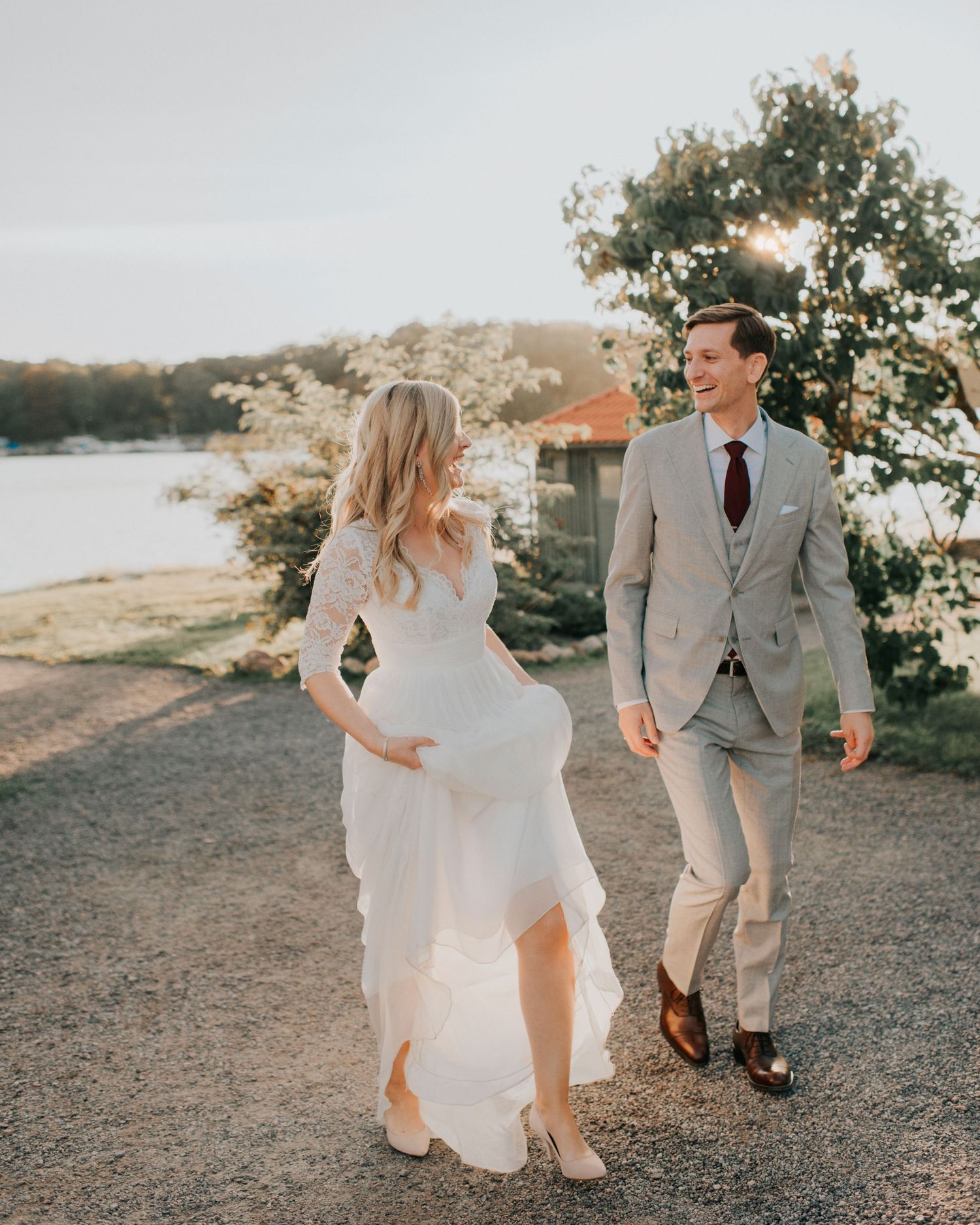 A couple enjoying playful moments on a coastal cliff in wedding attire.