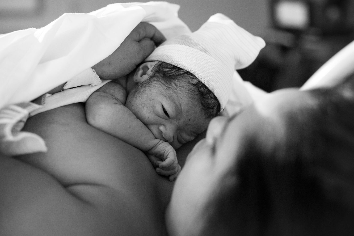Newborn born baby boy laying on mother's chest getting skin to skin after birth.