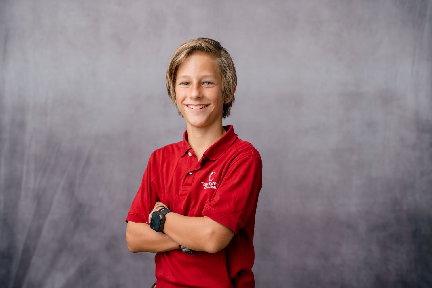 Person wearing red polo shirt posing against gray background.