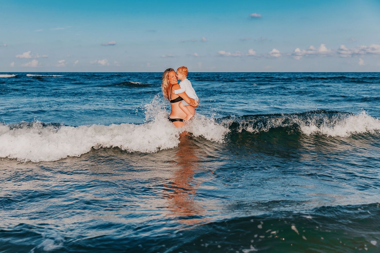 Ocean waves crashing on beach with blue water and sky on summer day.