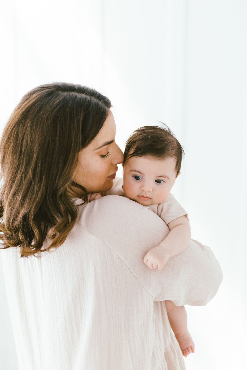 Sweet kisses and cuddles captured in a bright, airy studio setting.
