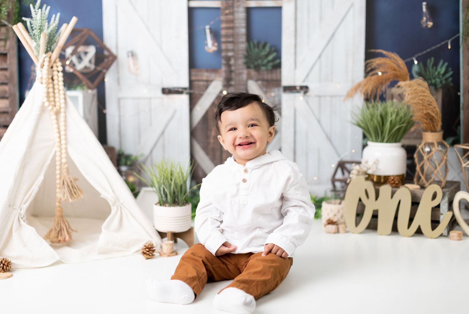 Modern farmhouse style photo setup with white barn doors and rustic elements.