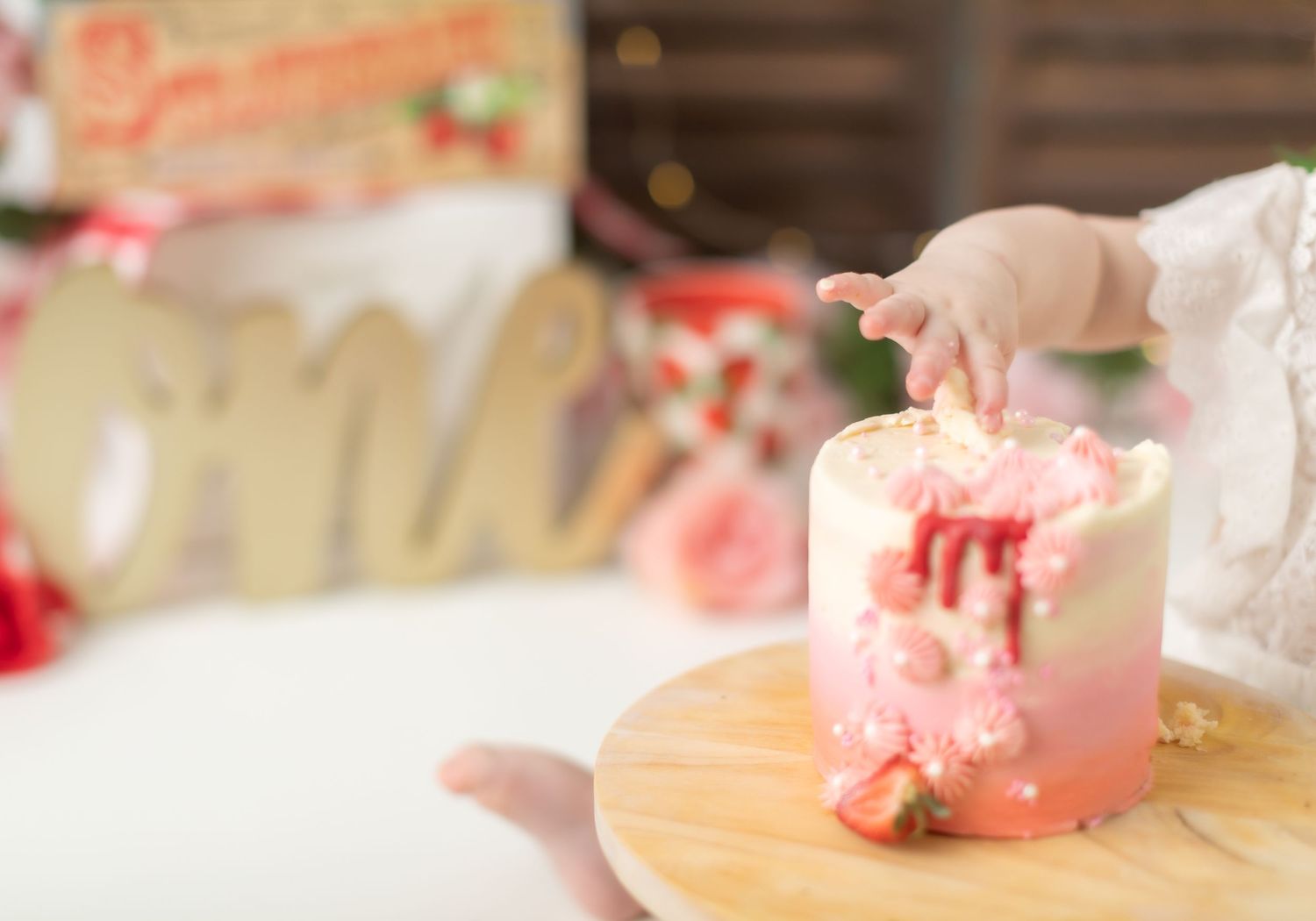 Close-up of pink strawberry themed cake with dripping frosting details.