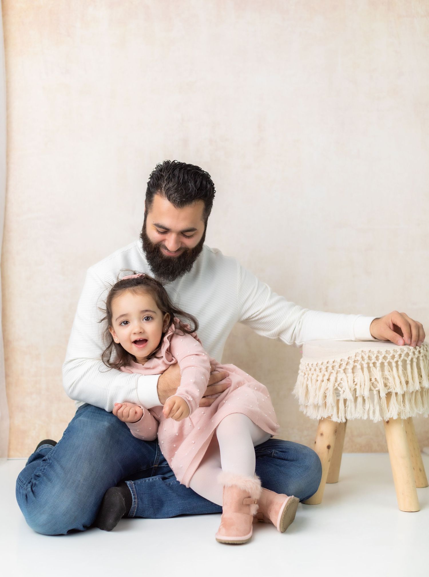 Cozy indoor portrait setup with neutral tones and macrame stool against beige wall.