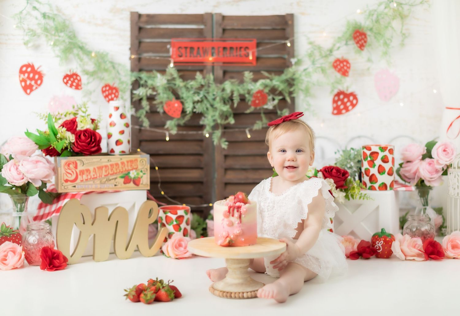 Strawberry themed cake smash setup with wooden crates and floral decorations.