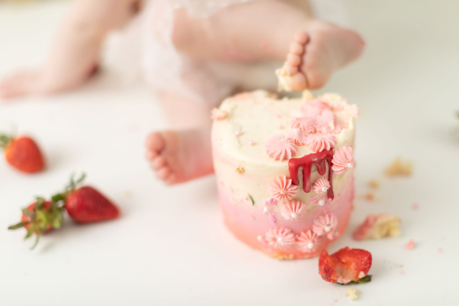 Detail shot of pink frosting and fresh strawberries during cake smash session.