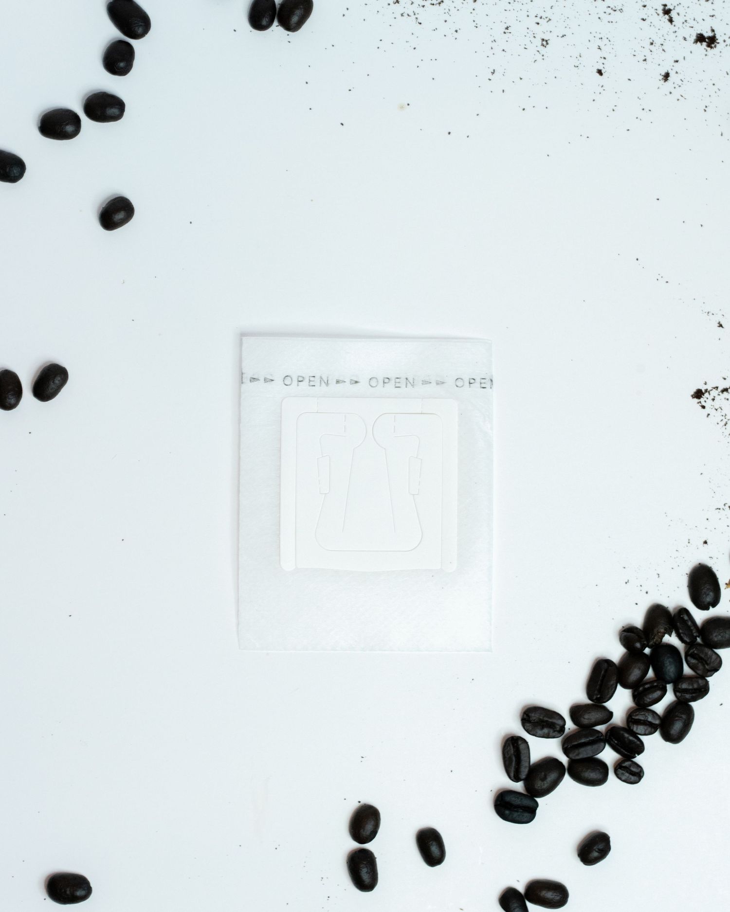 A flat detail layout of a portable pour over coffee filter on a white background with coffee beans on the edges