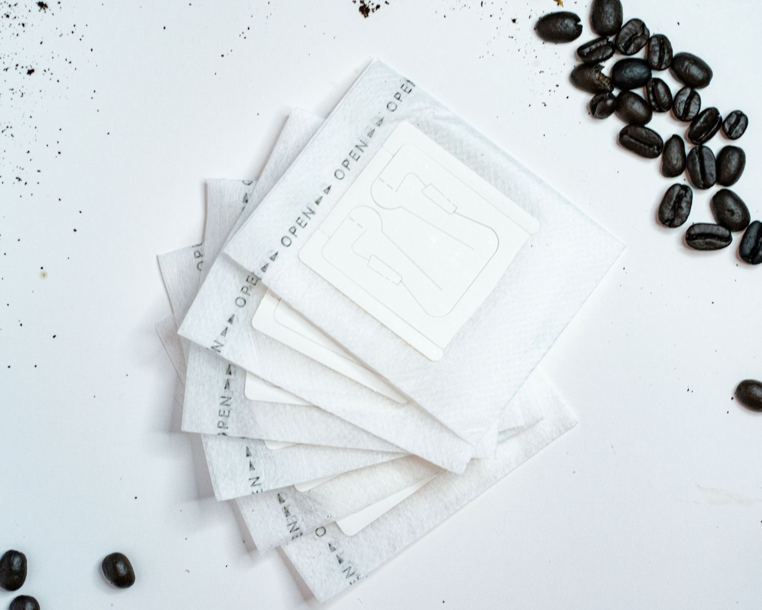 A flat detail layout of a portable pour over coffee filters on a white background with coffee beans on the edges