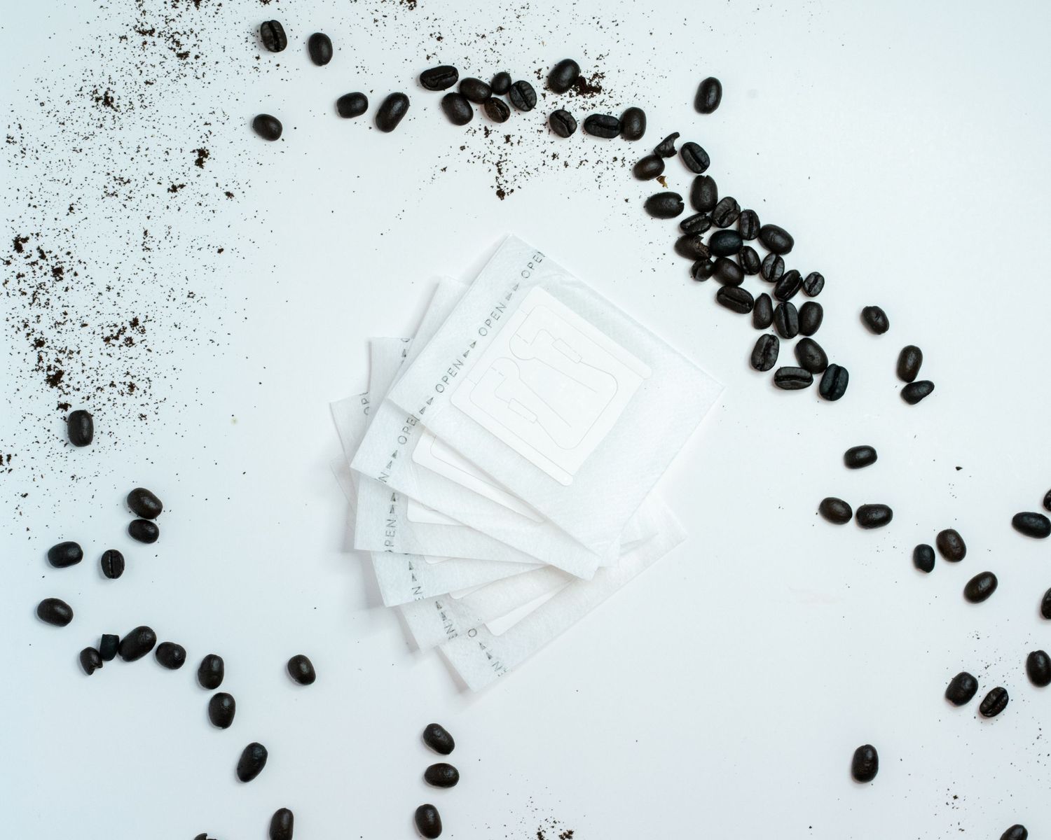 A flat detail layout of a portable pour over coffee filters on a white background with coffee beans on the edges