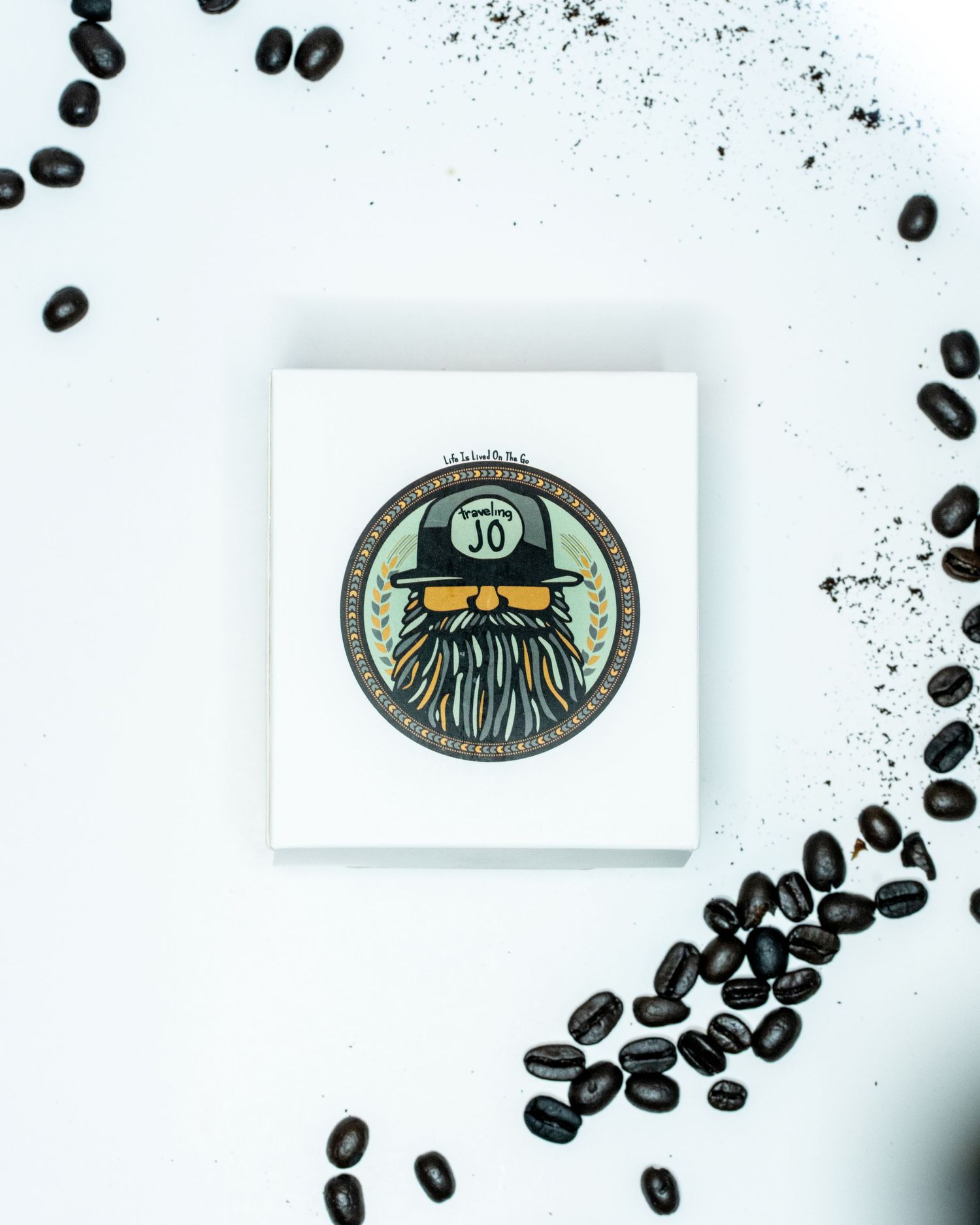 A flat detail layout of a white box and logo on a white background with coffee beans on the edges