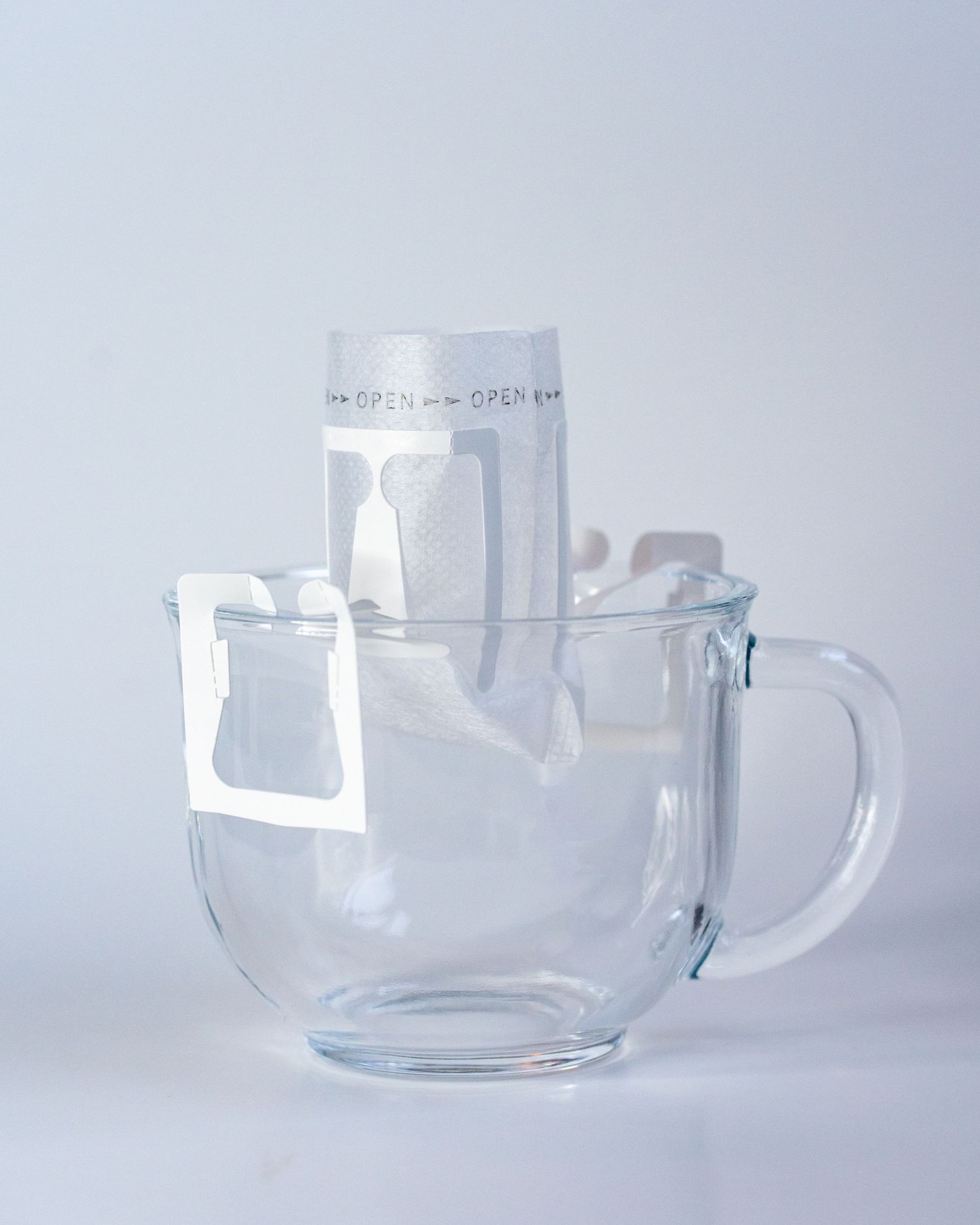 A glass mug in a white background holds a single lightweight pour over coffee filter