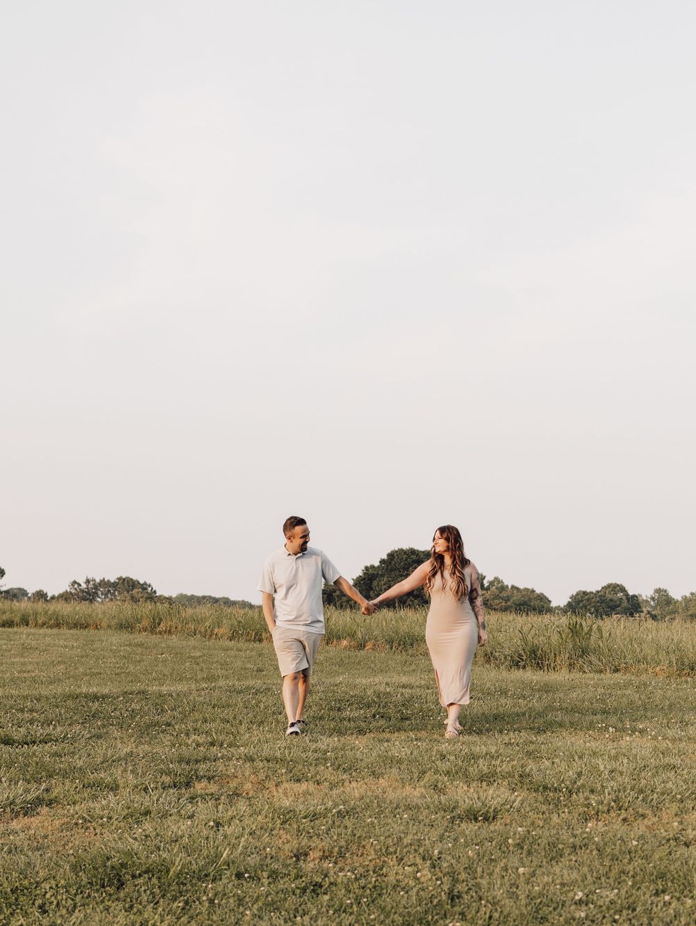 engaged couple walking through big field