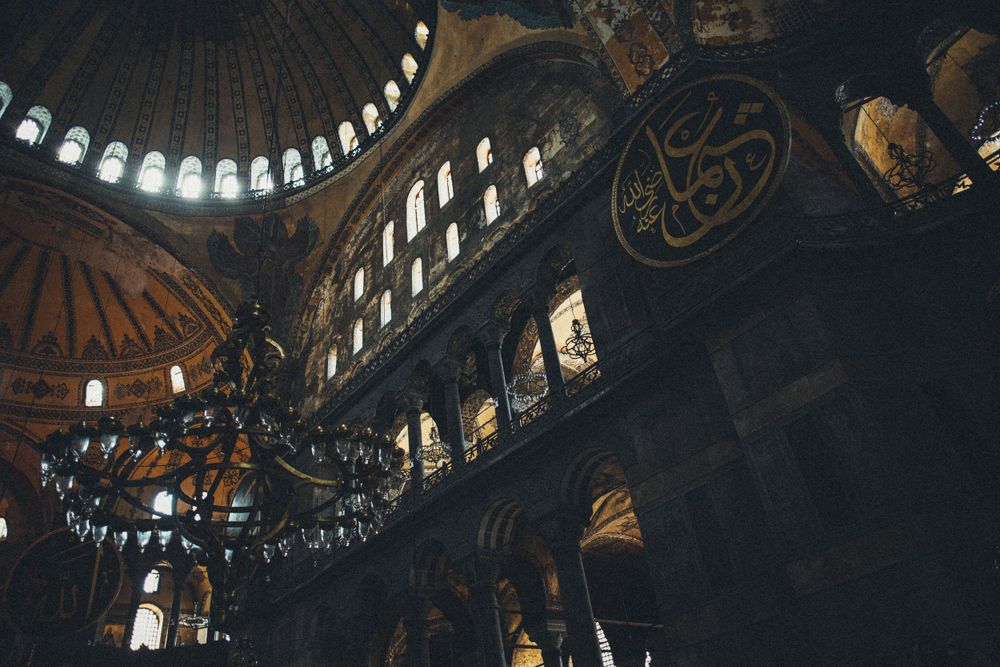 Ornate dome interior of Hagia Sophia with circular windows and Islamic architectural details.