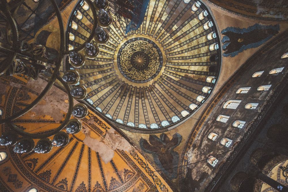 Golden sunburst pattern on historic dome ceiling with intricate Islamic artwork.