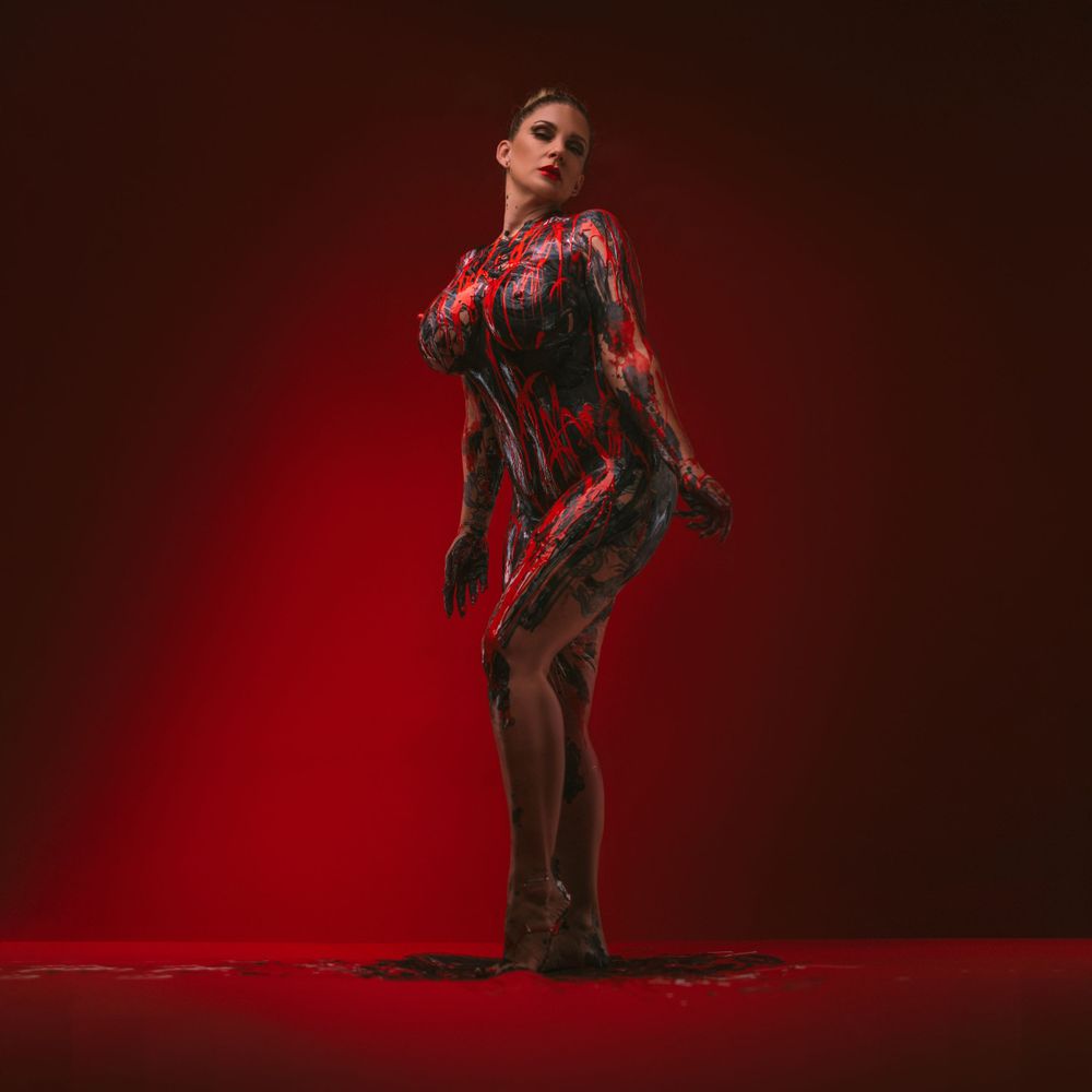 Dramatic silhouette pose against deep red background in artistic lighting.
