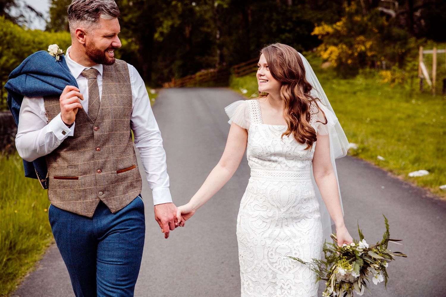 Couple walking down a country lane with autumn foliage and natural scenery.