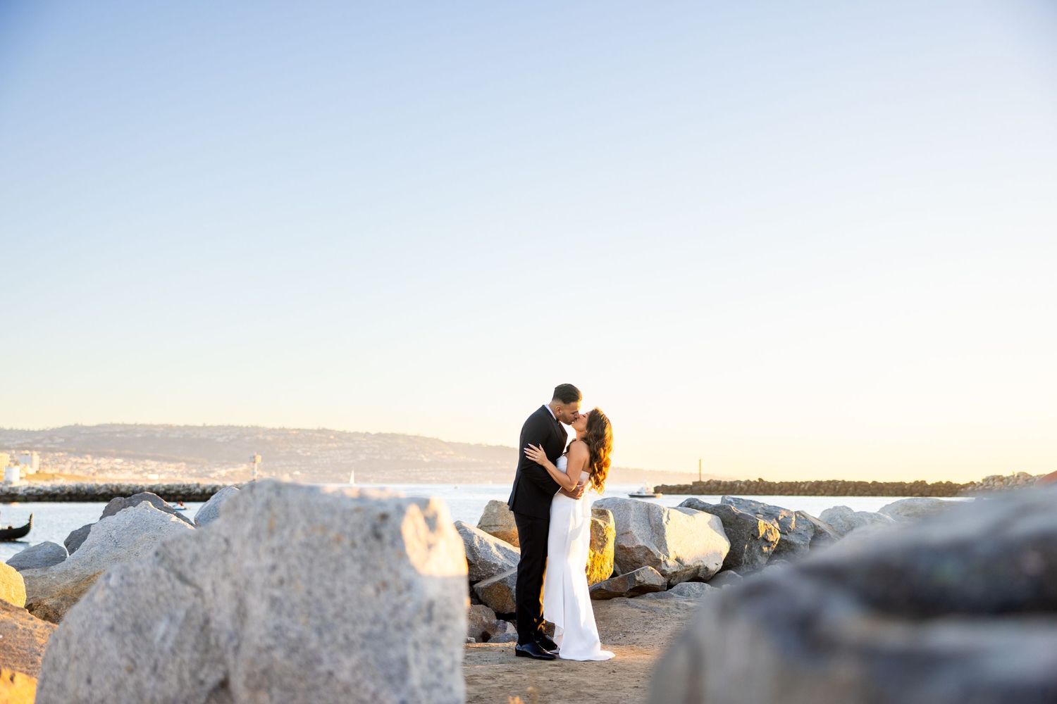 A romantic sunset wedding moment captured among white rocks overlooking the ocean.
