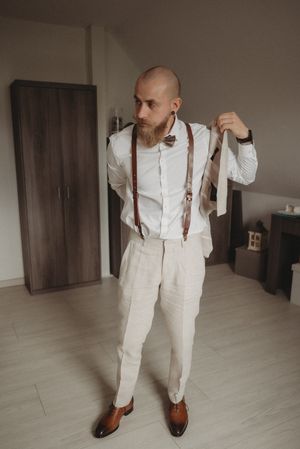 Dapper groom in vintage-inspired outfit with suspenders, bow tie and brown oxford shoes.