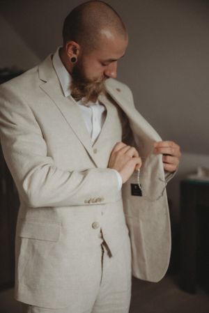 Close-up of hands adjusting the lapel of a light beige suit jacket.