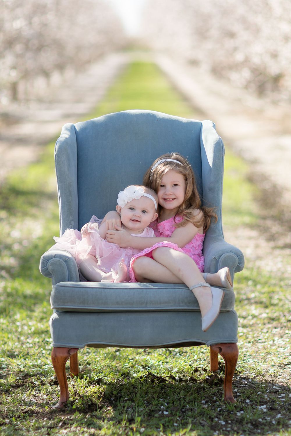 Two children sitting together on a vintage blue loveseat outdoors.