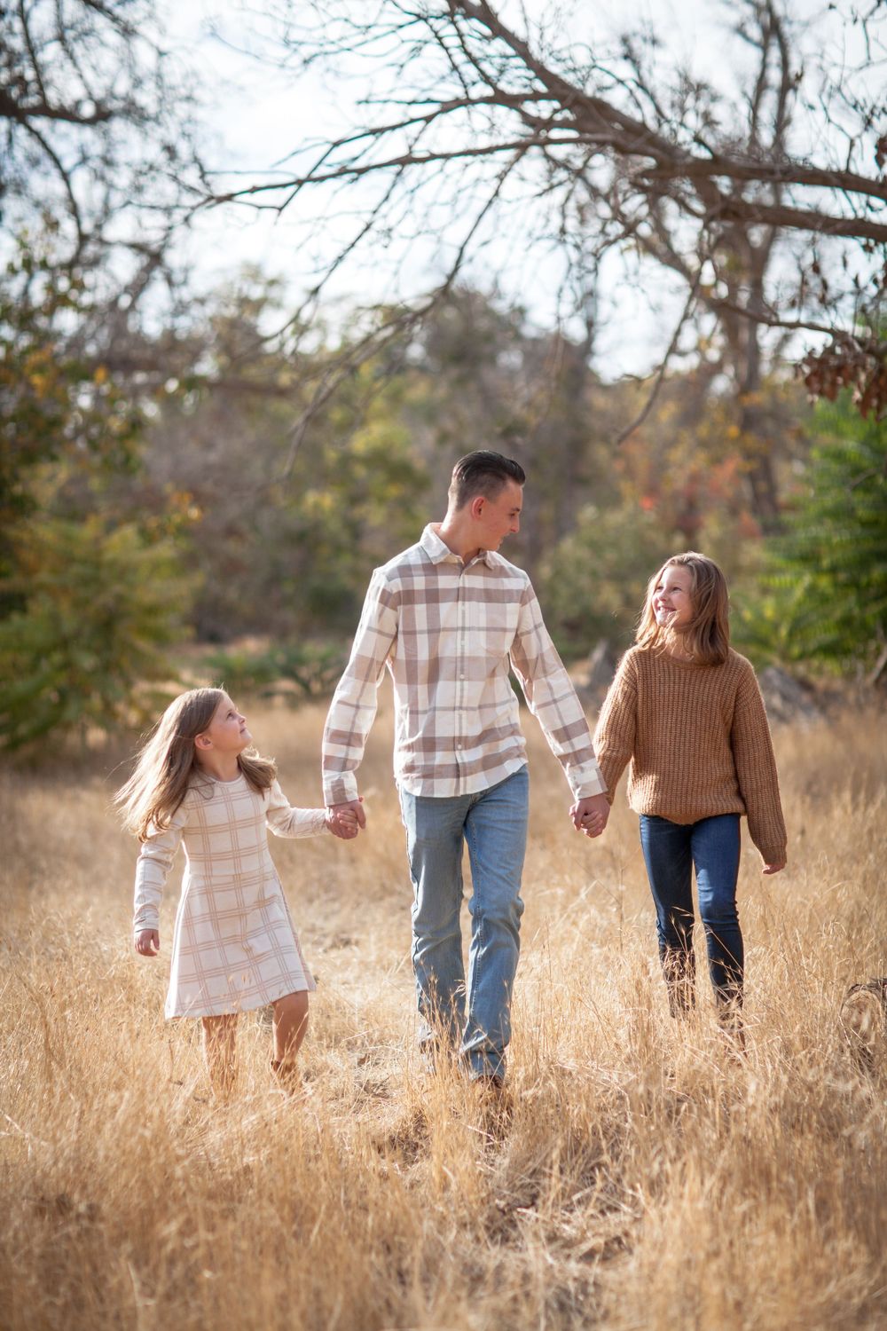 Family walking together through tall golden grass in a natural field setting.