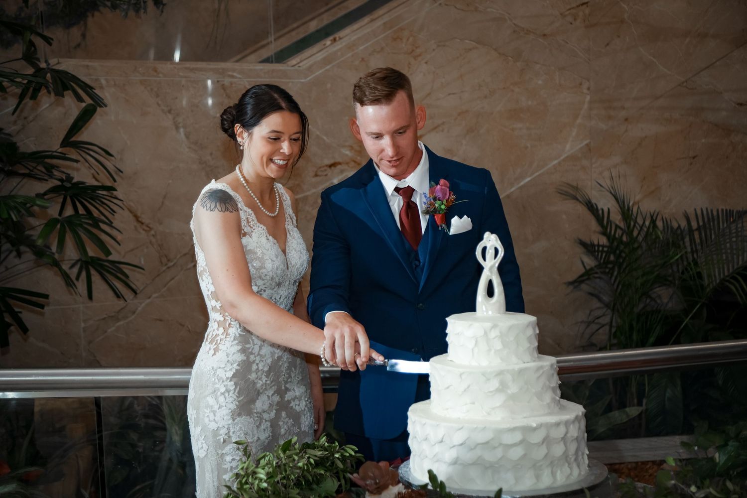 A couple cuts their classic white wedding cake together during their reception.