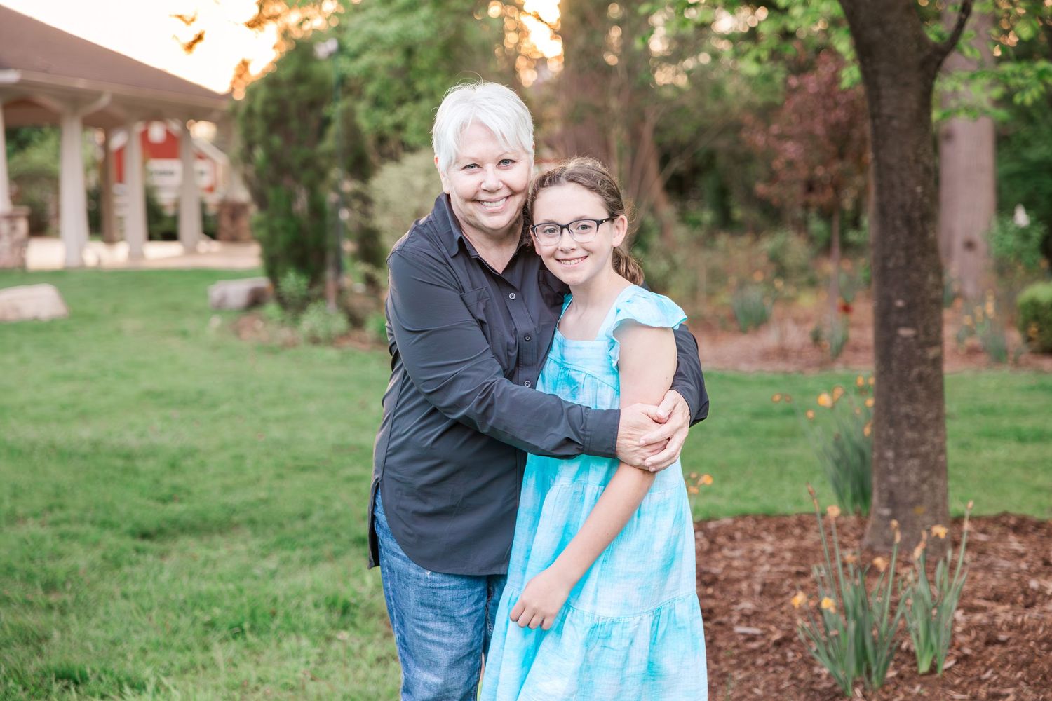 A tender embrace shared between two people in casual attire on a grassy lawn.